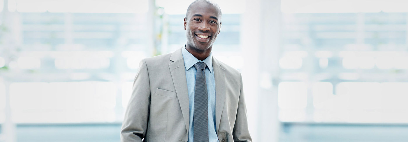 Business leader in grey suit smiles at the camera.