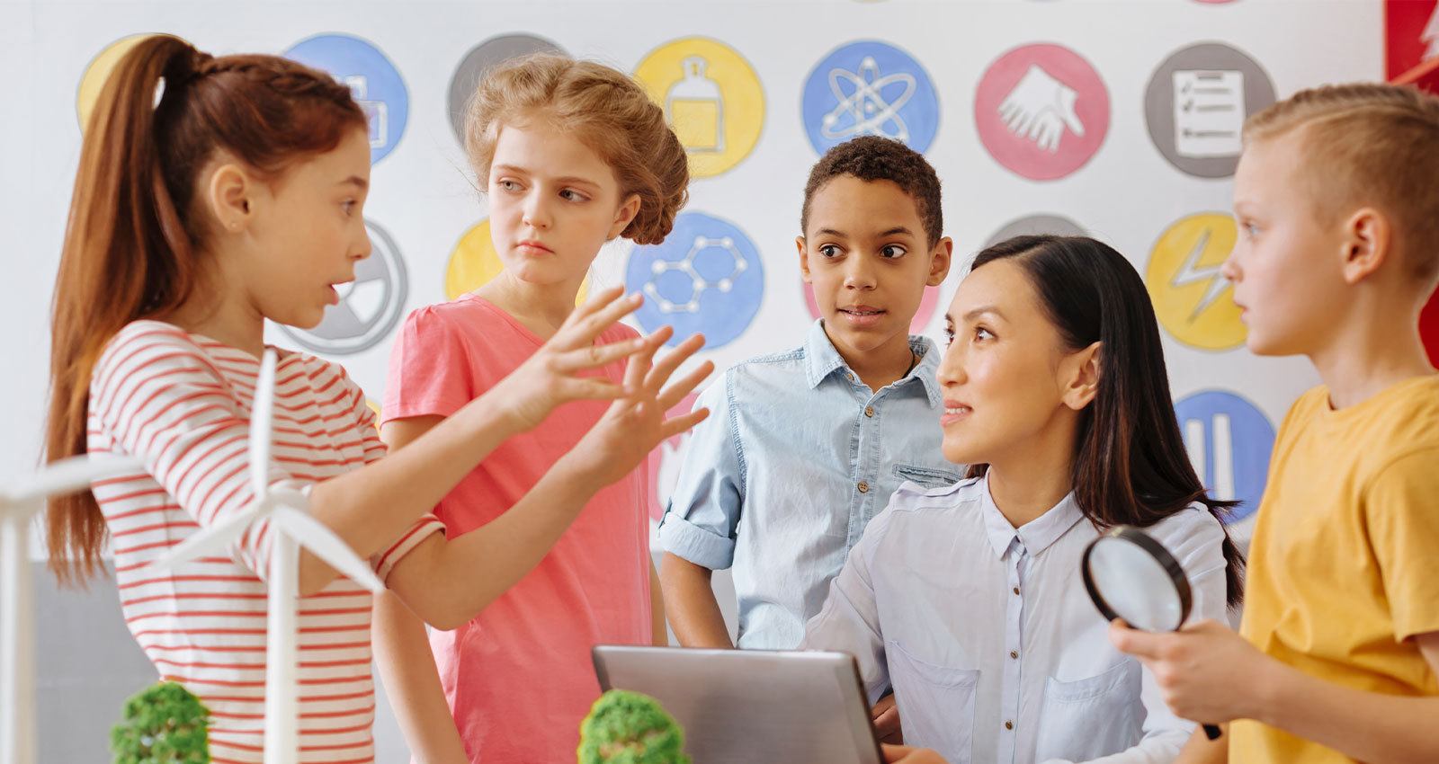 Elementary student gestures with her hands while sharing knowledge with her classmates.