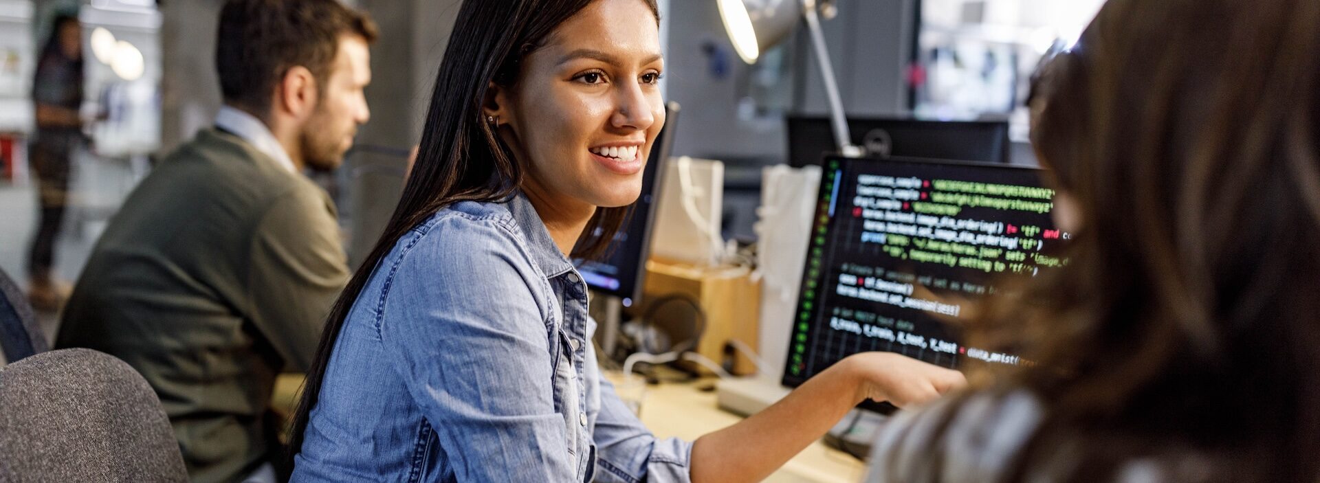 person chatting with someone while coding on a computer at a desk.