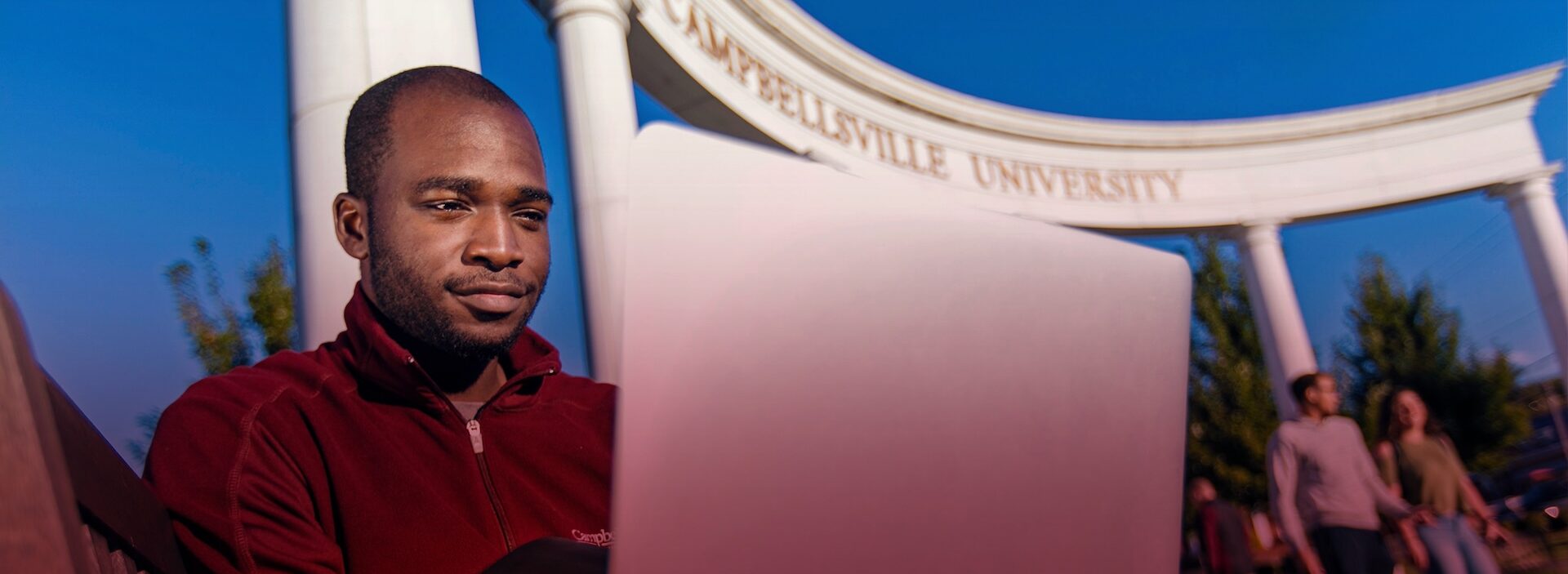 man sitting outside Campbellsville University studying