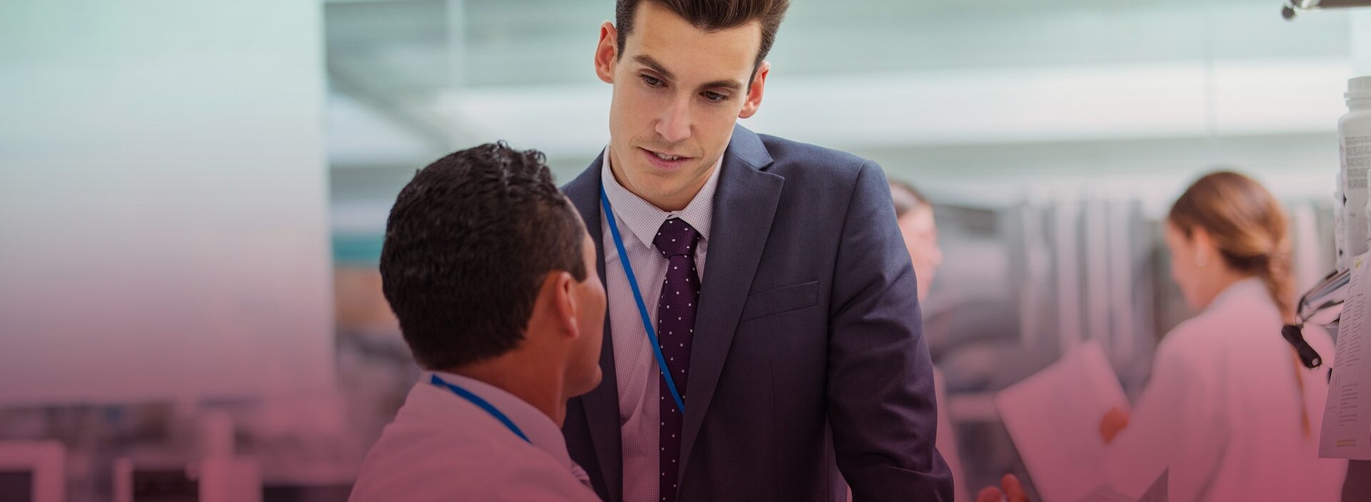 supervisor standing beside employee at desk in cubical