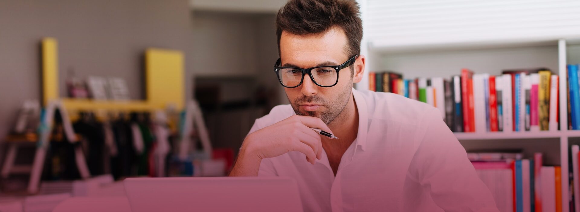 student studying at desk in front of bookcase in classroom