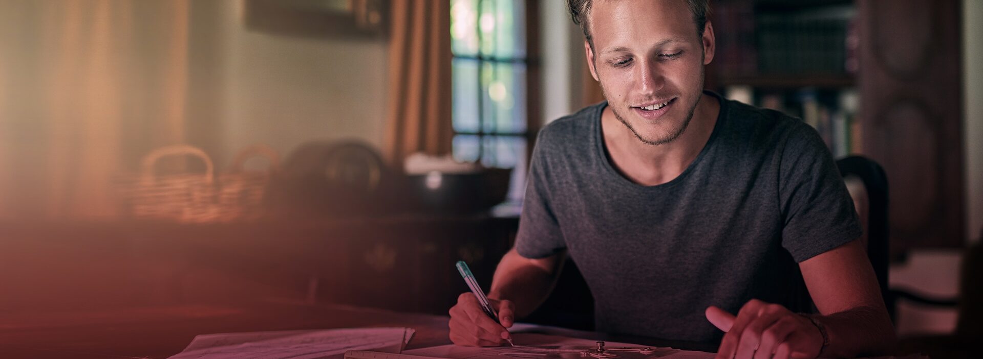 man filling out paperwork at dining table