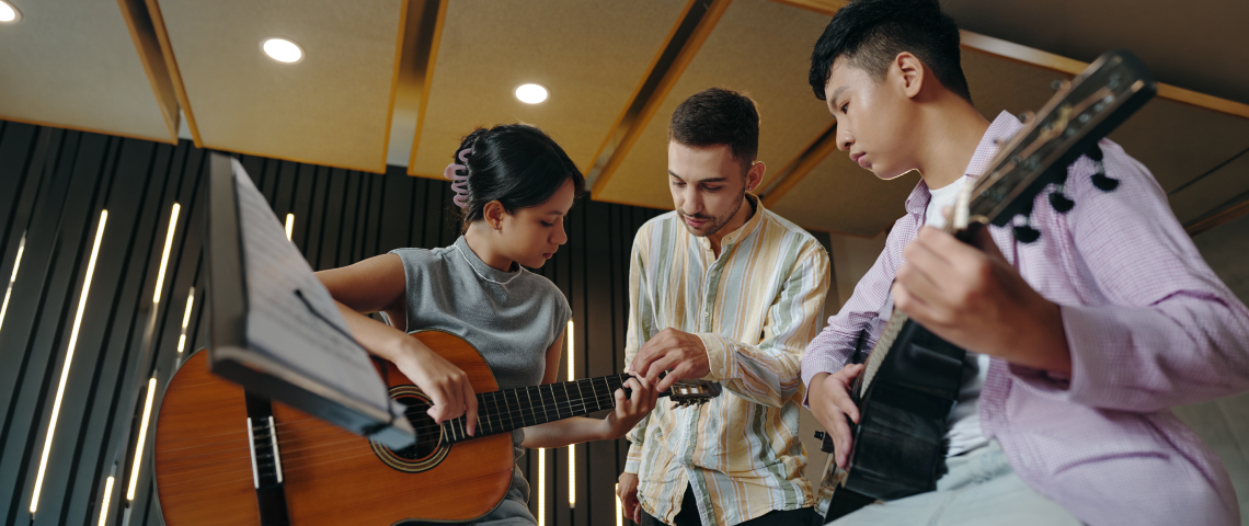 Three young musicians collaborating on guitar parts in a studio session