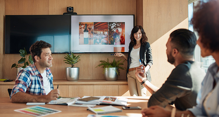 Female marketer leads presentation in wood accented conference room.