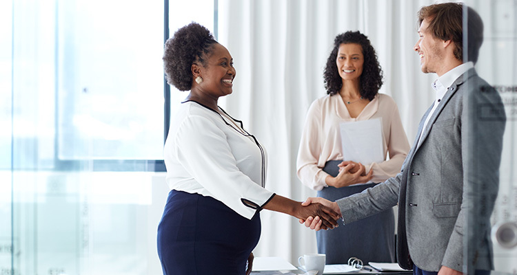 Business managers welcome new employee with a handshake.