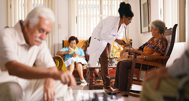 Female nurse taking the blood pressure of an elderly woman in a nursing home setting.